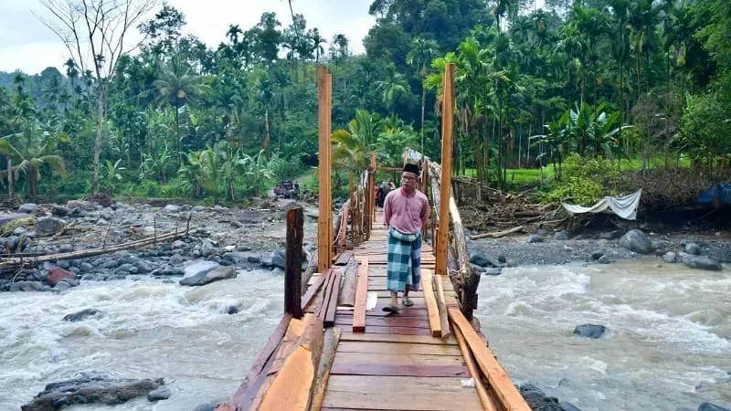 Warga melintasi jembatan darurat di Batang Mangui yang berada di Jorong Sini Air, Kecamatan Malalak Selatan, Kabupaten Agam. (Foto: Agam Media Center)
