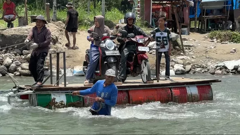 Warga di Kecamatan 2x11 Kayu Tanam, Kabupaten Padang Pariaman, menggunakan rakit darurat berbahan drum menyeberangi sungai setelah Jembatan Anduriang ambruk akibat banjir bandang pada November 2025. (Foto: Pemkab Padang Pariaman