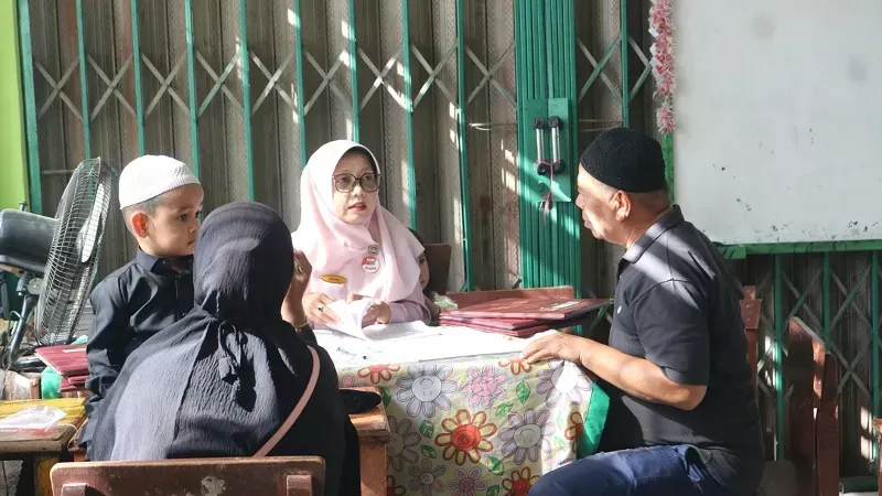 Seorang ayah mengambil rapor anaknya yang bersekolah di SDN 04 Terandam, Kota Padang. (Foto: Kominfo Padang)