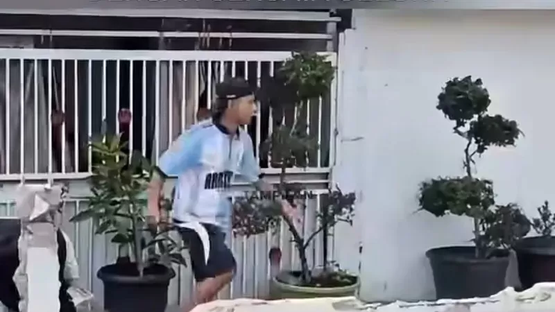 Pemilik rumah mengacungkan celurit saat Satpol PP Padang bersama tim gabungan membongkar pagar rumah yang menyerobot jalan. (Foto: Tangkap Layar Video Instagram Tampilancom)