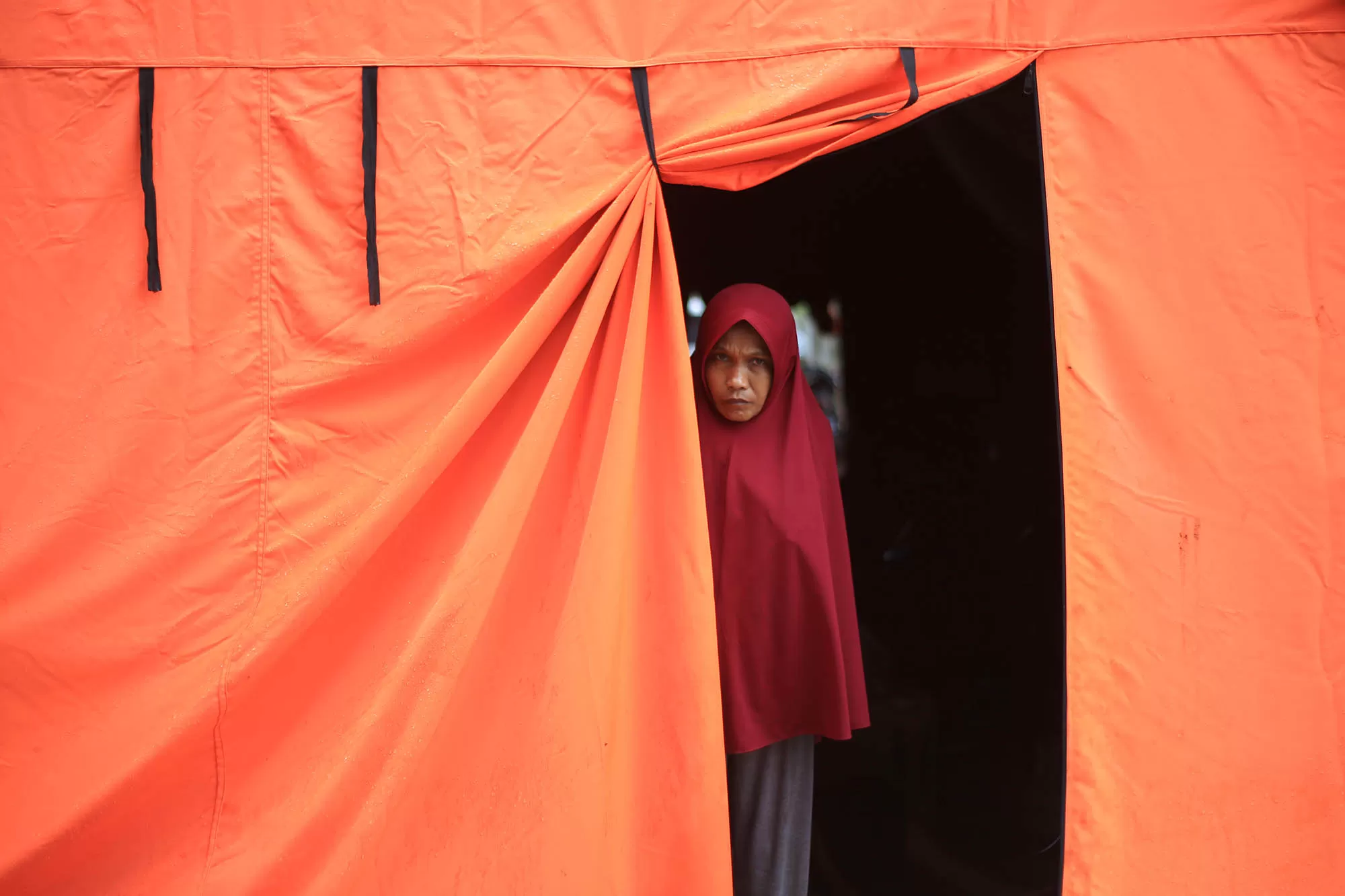 Pengungsi korban bencana banjir berdiri di pintu tenda darurat desa Meunasah Raya, kabupaten Pidie Aceh,  Aceh, Selasa (17/2/2026).  Puluhan KK pengungsi korban bencana di daerah itu larut dalam suasana kesedian menyambut tradisi Meugang Ramadhan 1447 Hijriyah, karena masih menempati tenda darurat sehubungan hunian sementara (Huntara)  belum tuntas dikerjakan. Aentenews Foto/Ampelsa.