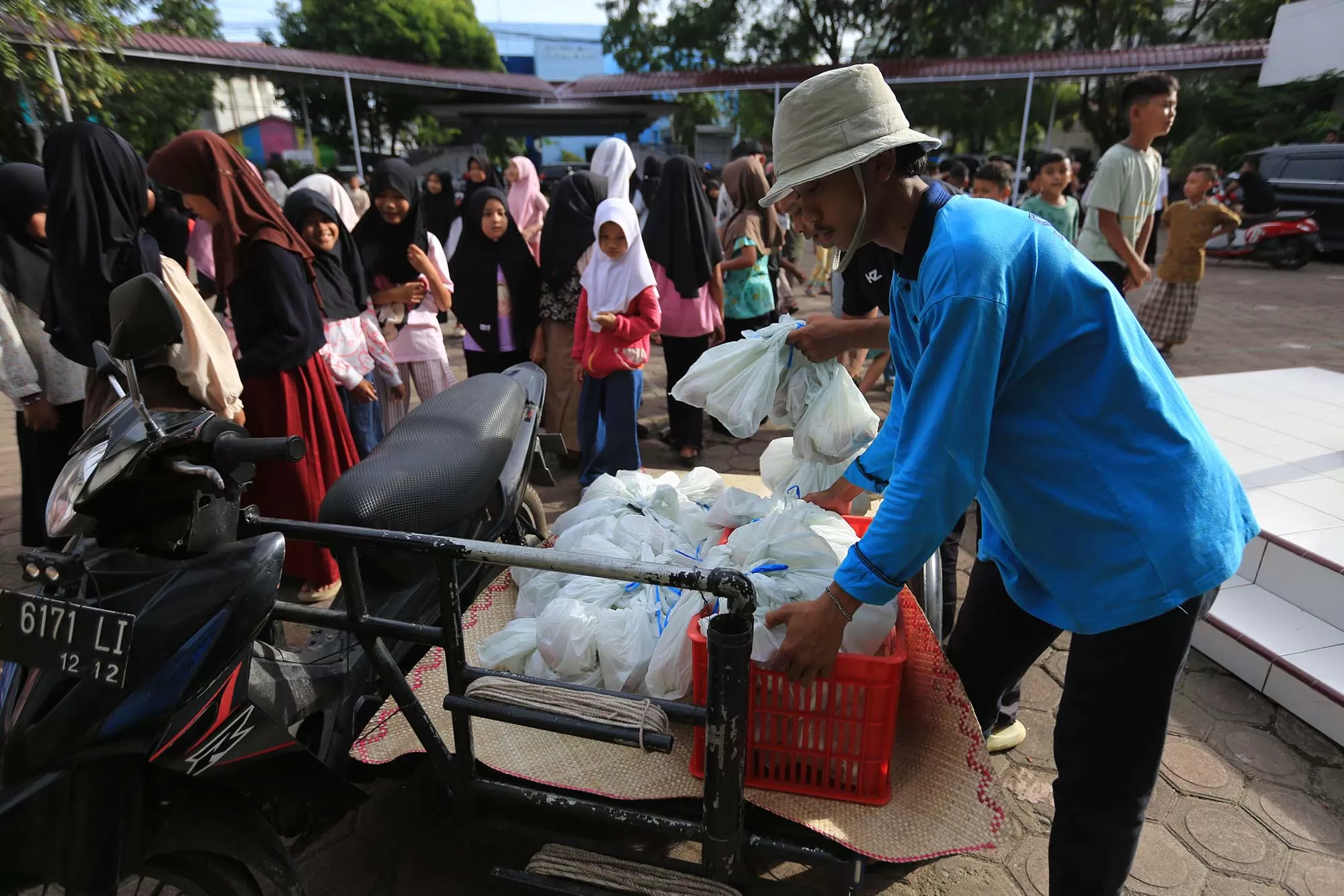 Petugas memindahkan menu MBG  yang diangkut menggunakan becak barang saat tiba di SDN 20 Banda Aceh, Senin (23/2/2026). Aentenews Foto/Ampelsa.