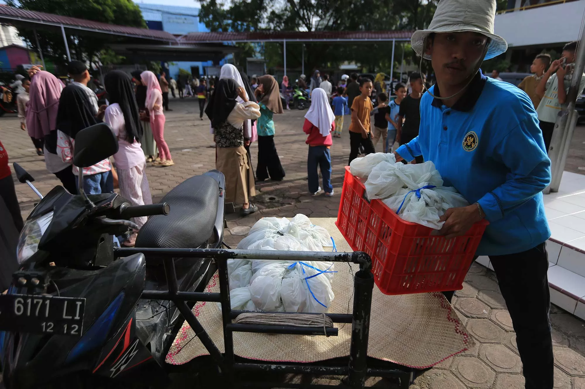 Petugas mengangkat makanan bergizi gratis yang dibungkus menggunakan kantong plastik  yang diangkut menggunakan becak saat tiba di SDN 20 Banda Aceh, Senin (23/2/2026). Penyaluran Makan Bergizi Gratis (MBG) dengan menu sebutir telur rebus, kurma, kacang goreng dan kanji atau bubur untuk bulan Ramadhan 1447 hijriyah di sekolah itu terlambat dari jawal yang ditentukan, sehingga ratusan orang tua bersama siswa antre lebih awal. Aentenews Foto/Ampelsa.