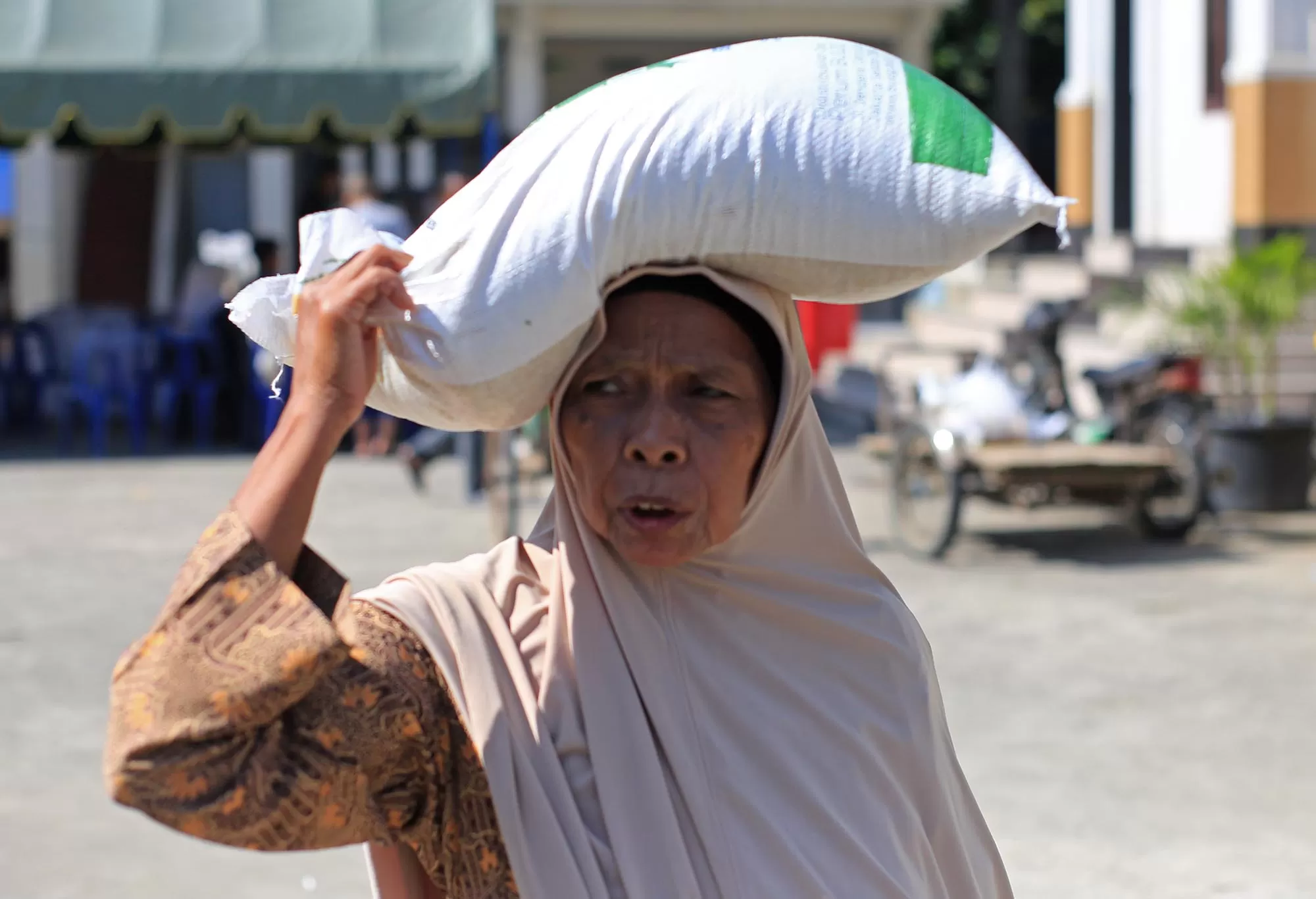 Warga memikul sekarung beras bantuan program pemerintah  seusai penyaluran di Desa Lampuuk kecamatan Kuta Baro, Aceh Besar Rabu (18/3/2026).  Aentenews Foto/Ampelsa.