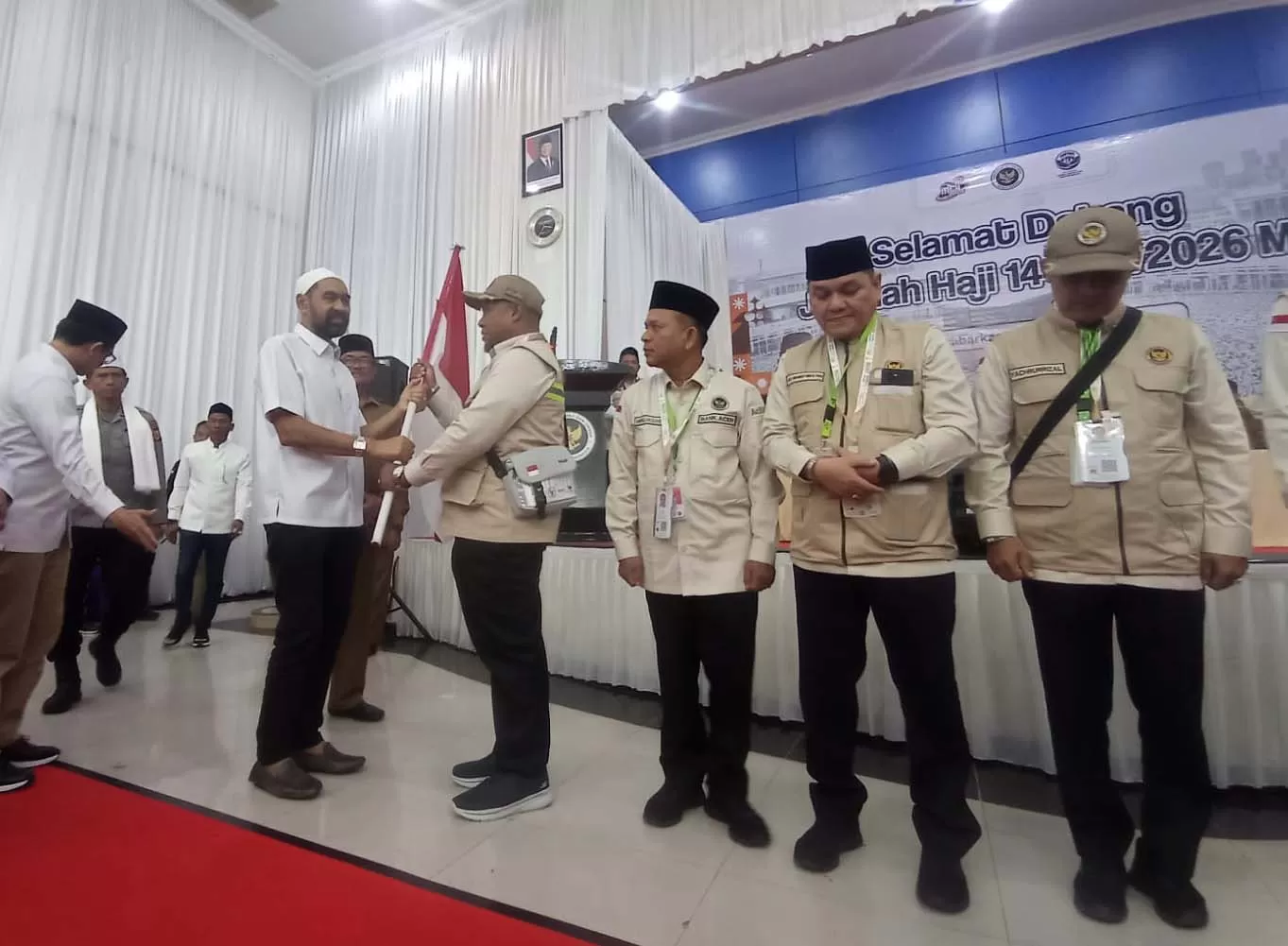 Gubernur Aceh, Muzakir Manaf (kiri) menyerahkan bendera kepada ketua kelompok terbang saat pelepasan calon jemaah haji kloter I di Embarkasi Haji Banda Aceh, Selasa (5/5/2026). Foto.dokumen PPIH