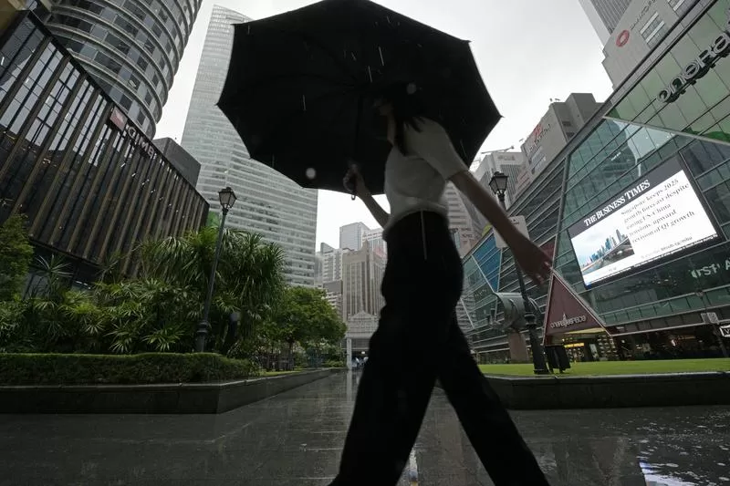 (250522) -- SINGAPORE, May 22, 2025 (Xinhua) -- A woman walks in the rain in Singapore's financial and business district Raffles Place on May 22, 2025. Singapore's economy expanded 3.9 percent in the first quarter from a year earlier, easing from 5.0 percent growth in the previous quarter, official data showed on Thursday. (Photo by Then Chih Wey/Xinhua)