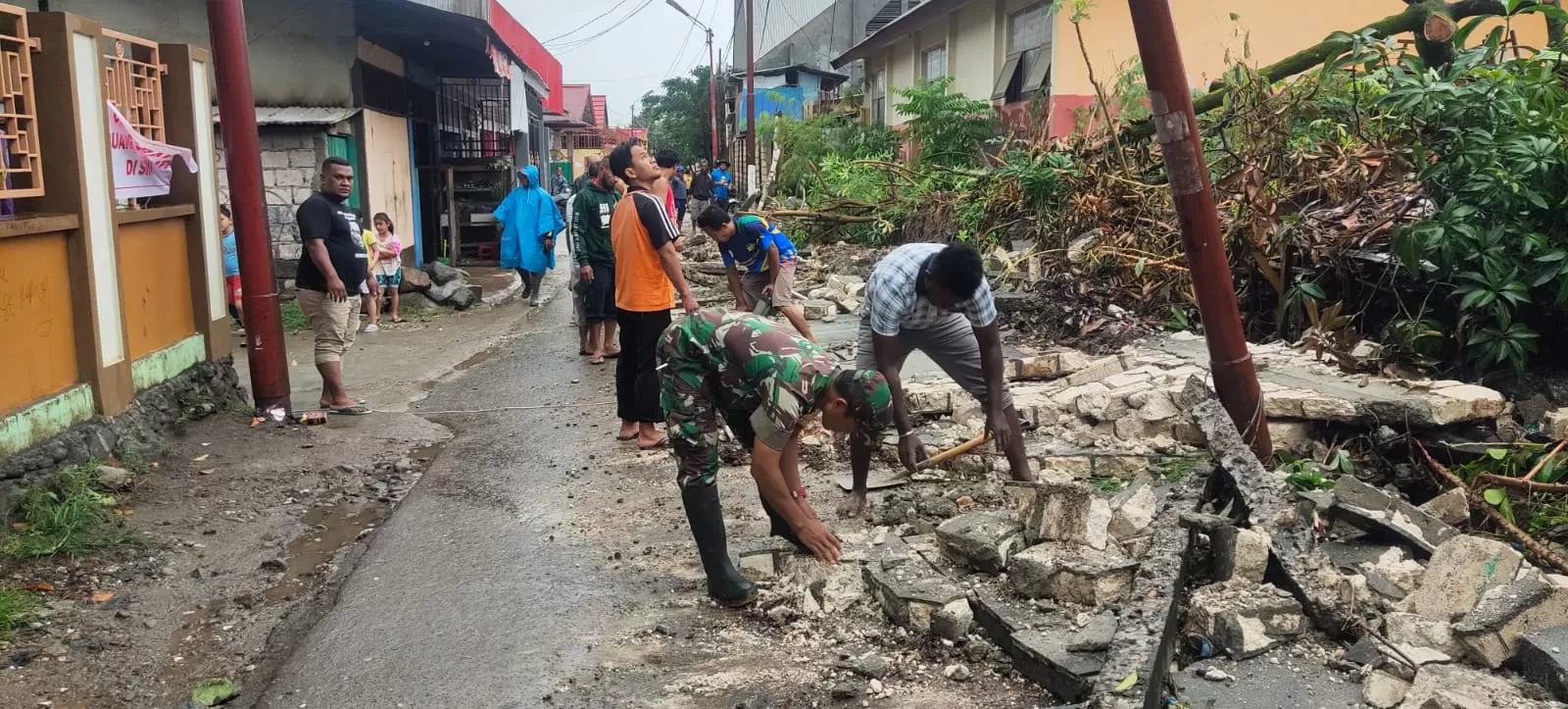 Anggota TNI bersama warga  saat membersihkan reruntuhan tembok yang menutup jalan akibat banjir yang terjadi  di  jalan masuk menuju Perumahan Organda Padang Bulan, Jumat (7/1). (Pendam for Cepos)