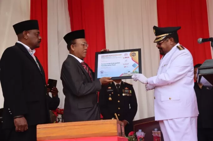 Bupati Mamberamo Raya Dr (HC) John Tabo, SE, MBA saat menyerahkan penghargaan BKN Award 2023 yang diperoleh Pemkab Mamberamo Raya kepada Sekda Manohar Sirait, SIP di sela acara HUT RI ke-78 di Burmeso Kabupaten Mamberamo Raya, Kamis   (17/8). Agung/Cepos