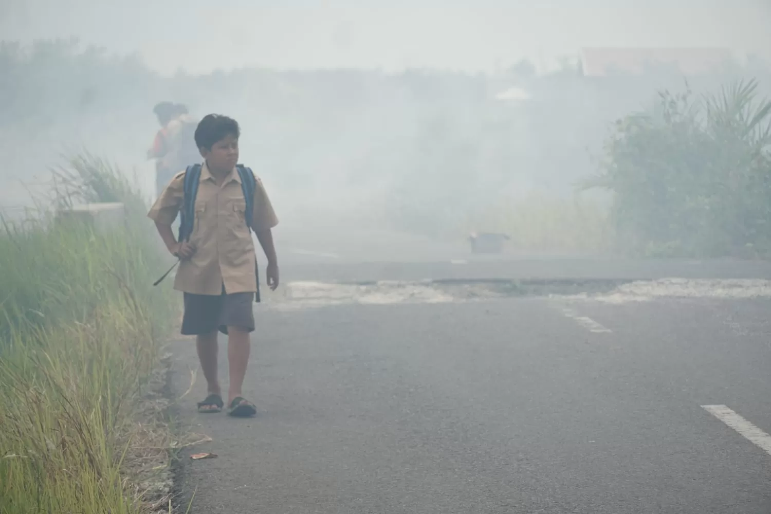 Seorang anak melintas di jalan Kota Palangka Raya, Kalimantan Tengah, di tengah asap dari kebakaran hutan di wilayah itu. Foto: Info Publik