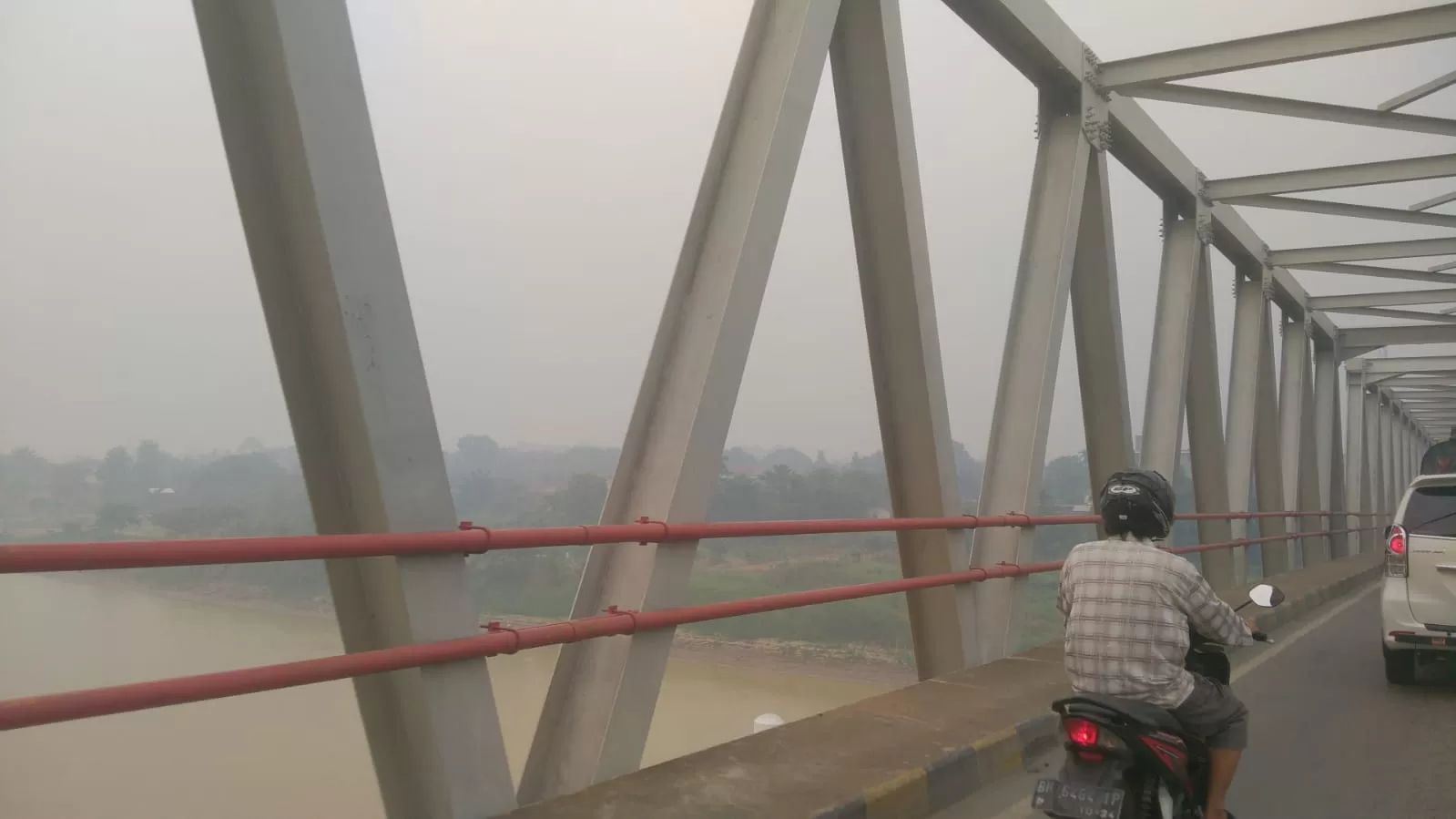 Seorang pengendara melewati jembatan di tengah kabut asap di Jambi. Foto: Ist  