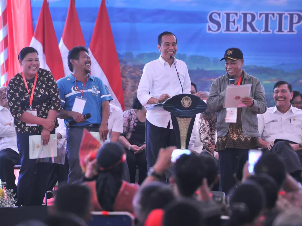 Presiden Jokowi tertawa saat berdialog dengan warga pada penyerahan sertipikat tanah untuk rakyat, di Dermaga Ajibata, Kabupaten Toba Samosir, Sumut, Selasa (30/7/2019)/JAY/Humas)