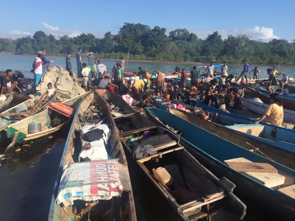 Sejumlah warga membantu memindahkan barang tidak terbakar saat terjadi peristiwa terbakarnya Kapal Motor (KM) Izhar di Perairan Bokori. (ANTARA FOTO/BASARNAS)