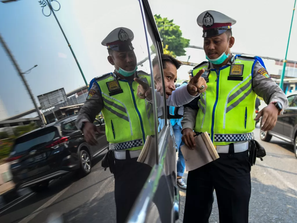 Polisi memberikan tilang kepada pengendara mobil yang melanggar di kawasan perluasan sistem ganjil genap. (Antara/Galih Pradipta)