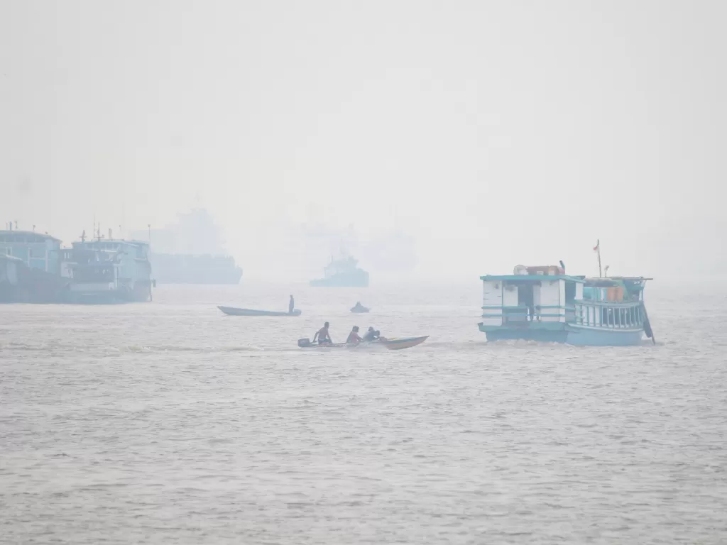 Sejumlah kapal melintasi Sungai Kapuas yang diselimuti kabut asap pekat di Pontianak, Kalimantan Barat. (Antara/Jesica Helena W)