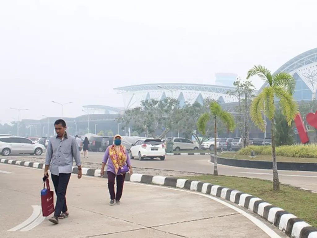 Warga berjalan di kompleks Bandara Supadio yang diselimuti kabut asap di Kabupaten Kubu Raya, Kalimantan Barat, Minggu (15/9). (Antara/Jessica Helena Wuysang)