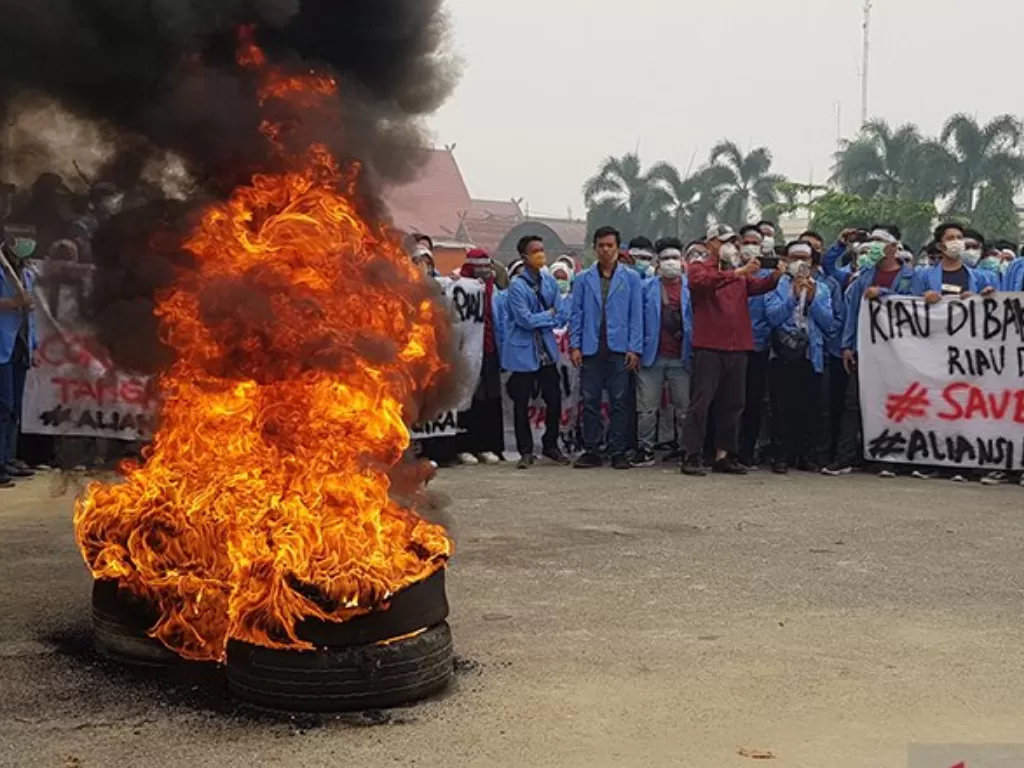 Ratusan mahasiswa dari Universitas Islam Negeri Sultan Syarif Kasim berunjuk rasa dengan membakar ban di depan gerbang Kantor Gubernur Riau di Pekanbaru. (Antara/FB Anggoro)