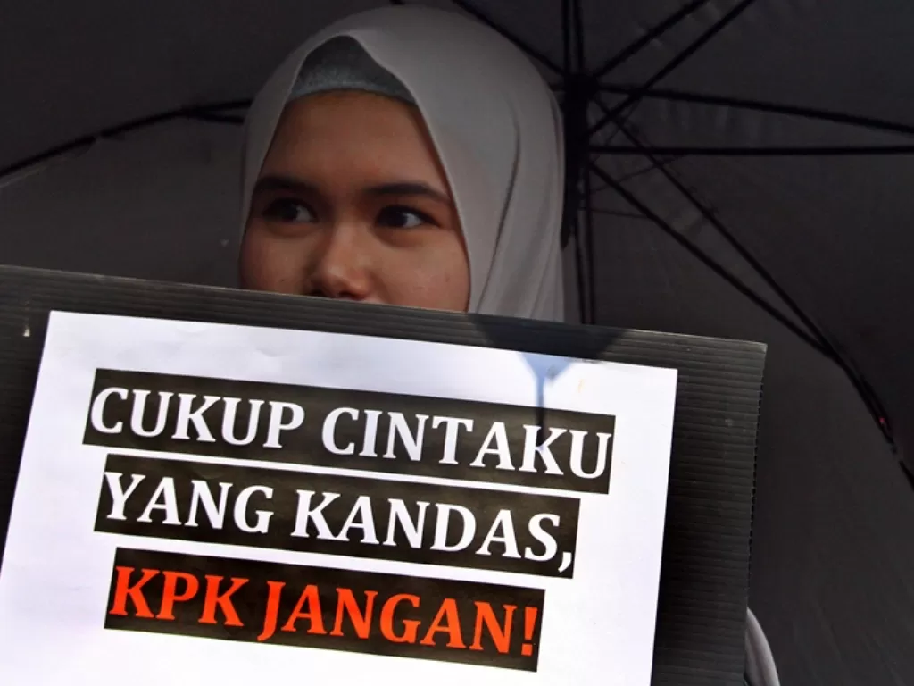 Anggota Aliansi Masyarakat Anti Korupsi (AMAK) membawa poster saat berunjuk rasa menolak pengesahan revisi UU KPK di depan Gedung DPRD, Malang, Jawa Timur, Rabu (18/9). (Antara/Ari Bowo Sucipto)
