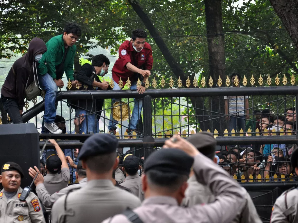 Sejumlah mahasiswa dari berbagai perguruan tinggi di Kota Medan menaiki pagar gedung saat melakukan aksi unjuk rasa di depan DPRD Sumut di Medan, Sumatera Utara, Selasa (24/9). (Antara/Septianda Perdana).