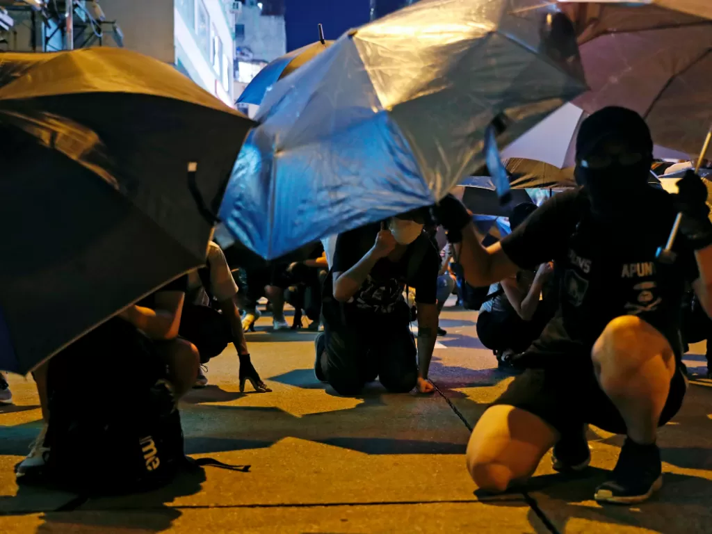 Pendemo anti ekstradisi berlindung dari serangan peluru karet di sekitar Kantor Polisi Mong Kok, Hong Kong, 6 September 2019. (Reuters/Tyrone Siu)