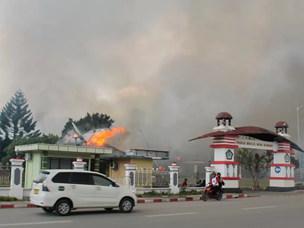  Pengendara melintasi Kantor Bupati Jayawijaya yang terbakar saat aksi unjuk rasa yang berujung kerusuhan di Wamena, Jayawijaya, Papua, Senin (23/9). (Antara/Marius Wonyewun).