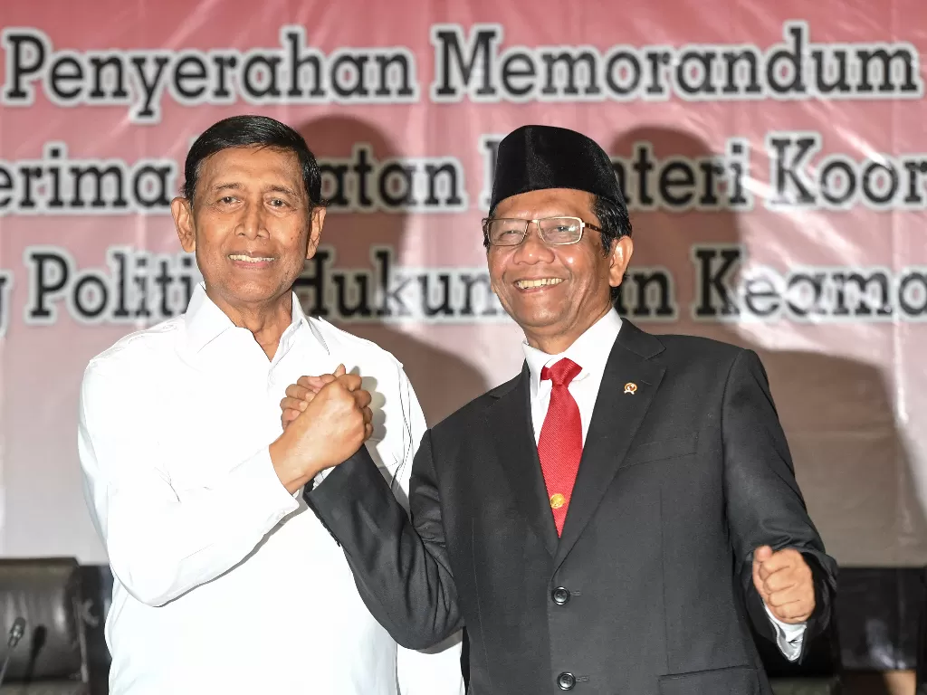 Menkopolhukam Mahfud MD (kanan) berjabat tangan dengan pejabat lama Wiranto saat serah terima jabatan di kantor Kemenkopolhukam, Jakarta, Rabu (23/10). (Antara/Hafidz Mubarak A)