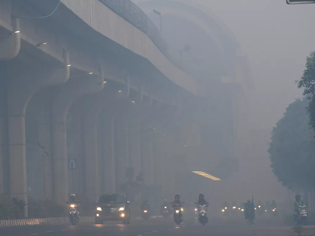 Sejumlah kendaraan melintas di Jalan Gubernur Ahmad Bastari Palembang yang diselimuti kabut asap. (Antara/Nova Wahyudi)