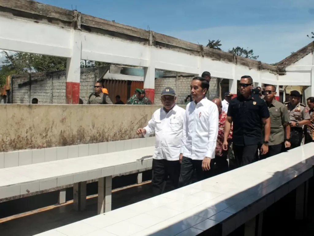 Presiden Jokowi (kanan) didampingi Menteri PUPR Basuki Hadimuljono (kiri) meninjau kondisi Pasar Wouma yang terbakar saat kerusuhan lalu di Wamena, Senin (28/10). (Antara/Marius Wonyewun)