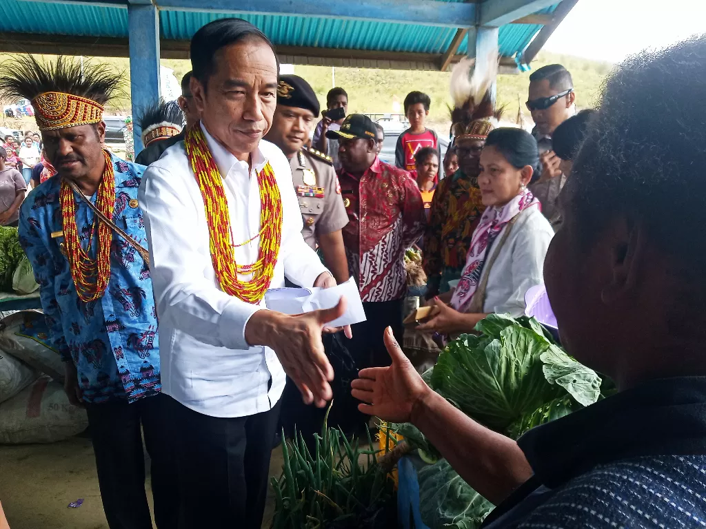 Presiden Jokowi (kedua kiri) bersama Ibu Negara Iriana Joko Widodo (ketiga kanan) menyapa warga saat meninjau pasar khusus Mama Papua di Papua Barat, Minggu (27/10). (Antara/Thoyib)