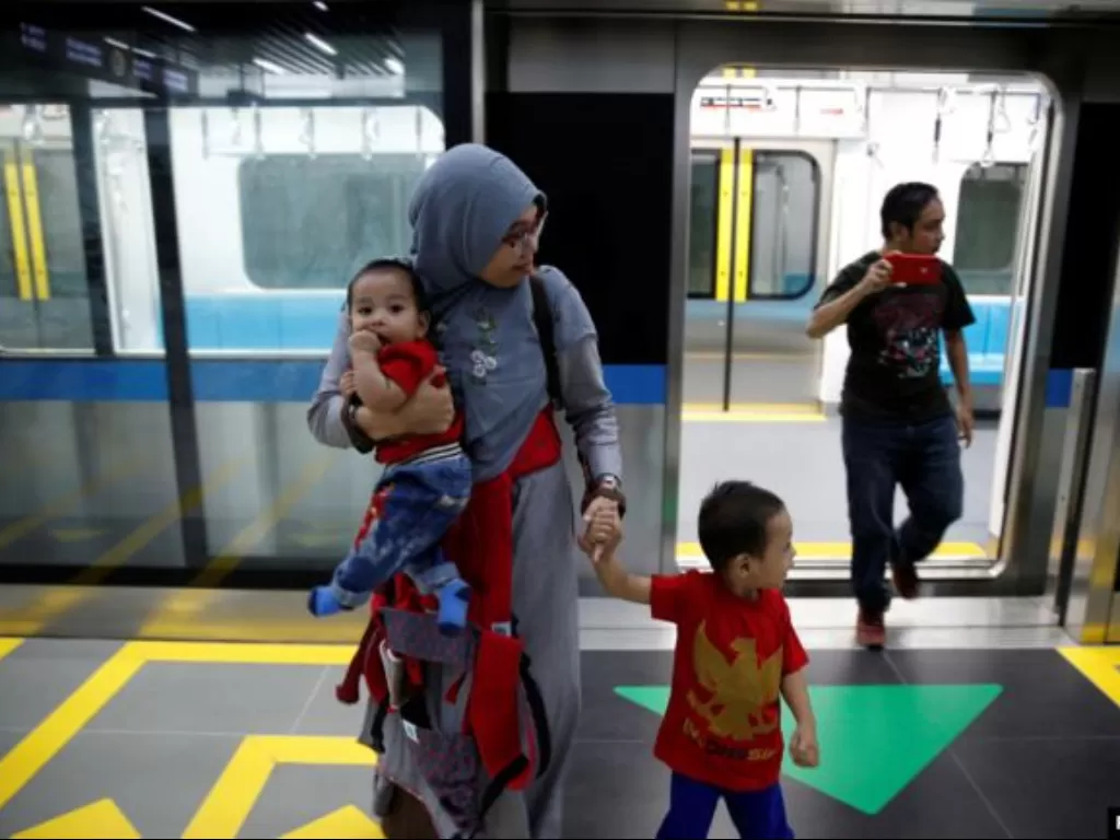 Seorang perempuan bersama anak-anaknya tiba di di sebuah stasiun saat uji coba Moda Raya Terpadu (MRT) di Jakarta, 12 Maret 2019. (Reuters)