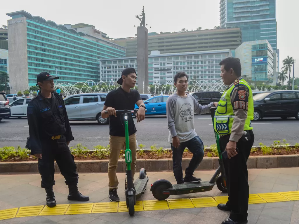 Sejumlah anggota kepolisian memberi himbauan kepada pengguna skuter listrik yang melintasi kawasan Bundaran HI, Jakarta Pusat. (Antara/ Fakhri Hermansyah)