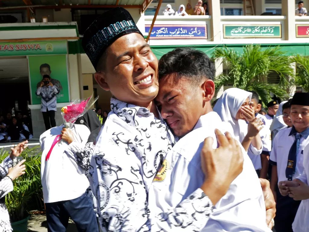 Pelajar memberikan ucapan selamat dengan memeluk gurunya seusai upacara peringatan Hari Guru Nasional di MTsN Model, Banda Aceh, Aceh, Senin (25/11). (Antara/Irwansyah Putra)