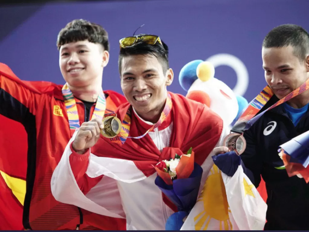Lifter Indonesia, Deni (tengah) tampil perkasa dengan medali emas. (Twitter/@The2019SEAGames)