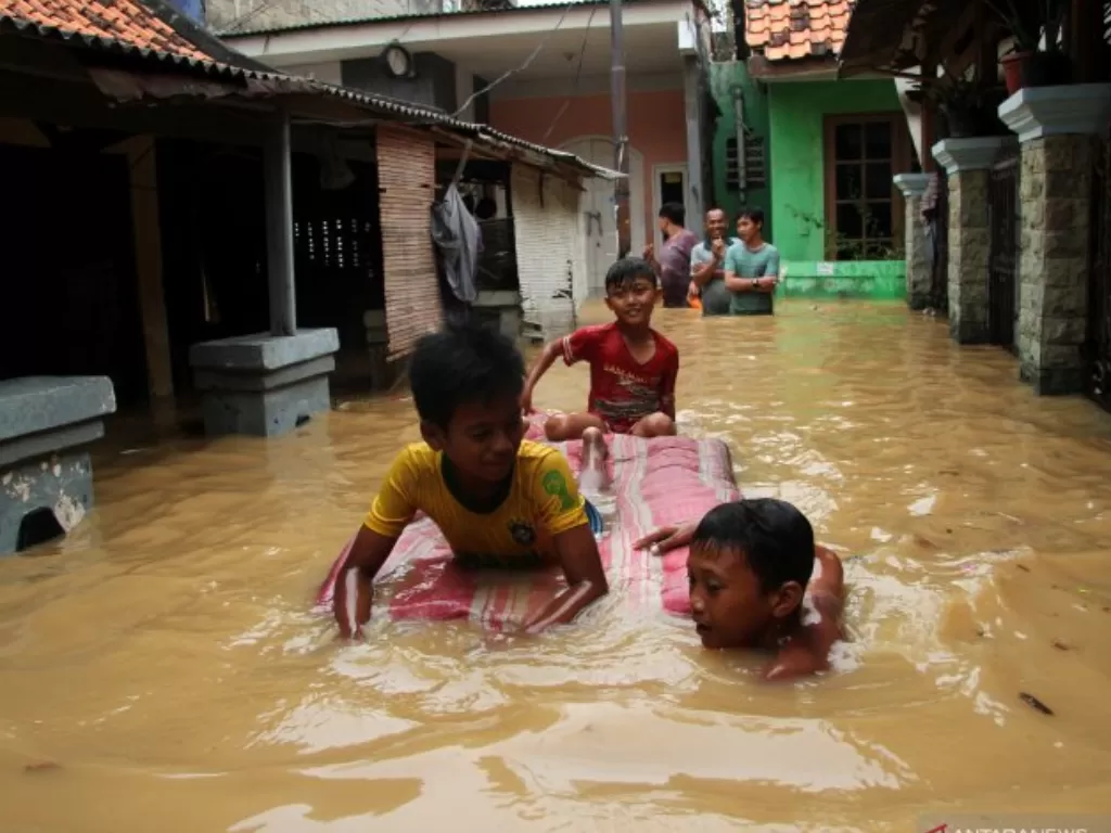 Sejumlah anak bermain air banjir yang merendam kawasan permukiman penduduk Cililitan Kecil, Jakarta, Jumat (26/4/2019). (Antara/Risky Andrianto).