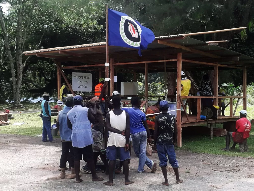 Warga memegang bendera Bougainville di tempat pemungutan suara selama referendum kemerdekaan. (Reuters/Melvin Levongo)