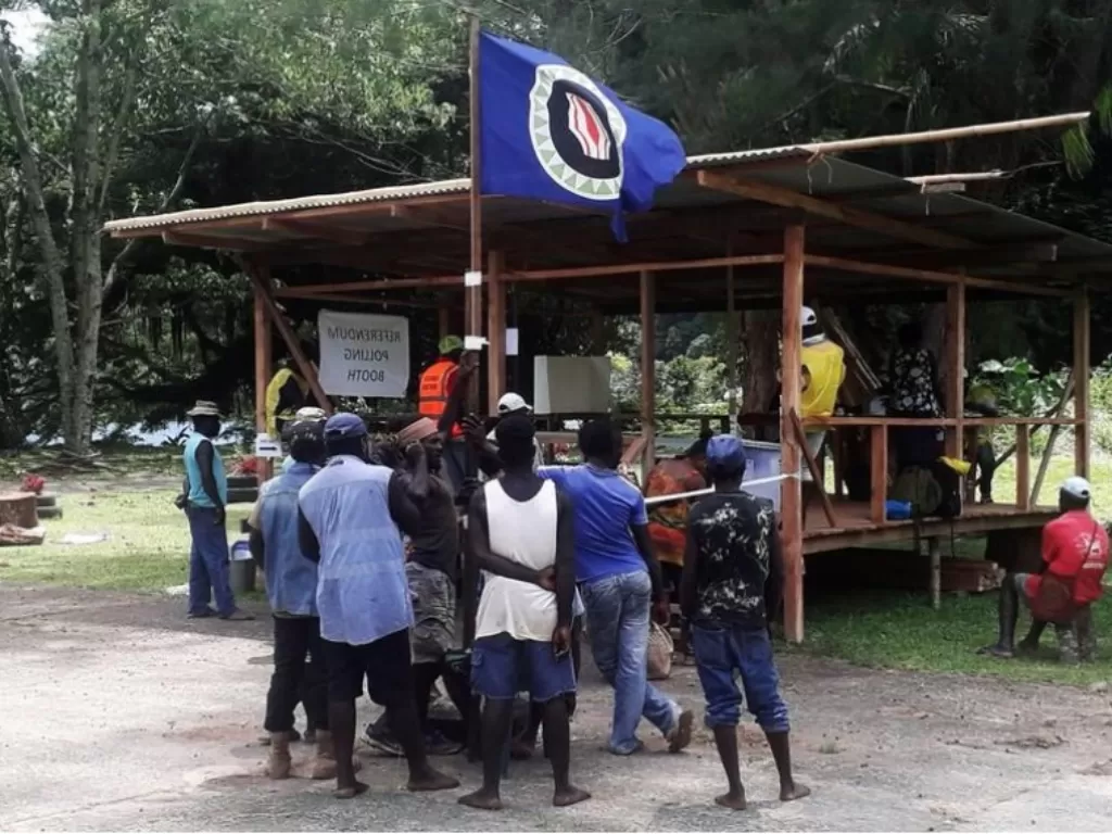 Warga memegang bendera Bougainville di tempat pemungutan suara saat referendum kemerdekaan (Reuters/Melvin Levongo)