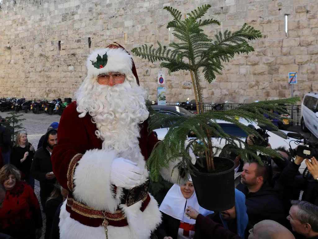 Issa Kassissieh mengenakan kostum Sinterklas saat membagikan pohon natal gratis di Kota Tua Yerusalem, 19 Desember 2019. REUTERS/Ammar Awad