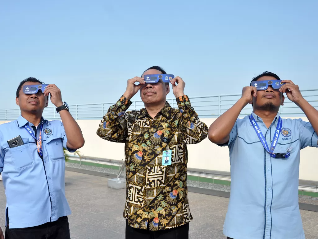 Rektor Universitas Muhammadiyah Sumatera Utara (UMSU) Agussani (tengah) bersama jajarannya memperlihatkan kacamata khusus melihat matahari yang akan digunakan untuk mengamati Gerhana Matahari Cincin di Observatorium Ilmu Falak UMSU, Medan, Senin (23/12). 