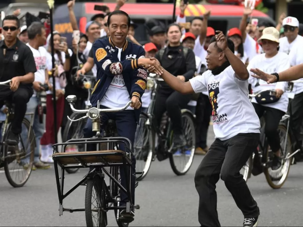 Presiden Jokowi menyenmpatkan diri bersalaman dengan warga saat sedang mengayuh sepeda ontel di Yogyakarta. (Antara/Puspa Perwitasari)