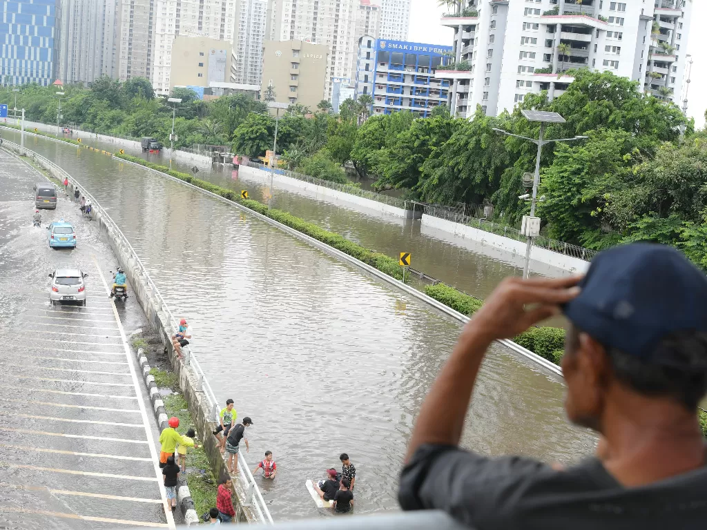 Warga mengamati banjir yang merendam Jalan Letjen S Parman dan tol dalam kota di Jakarta Barat, Rabu (1/1/2020).(ANTARA FOTO/Nova Wahyudi/aww).
