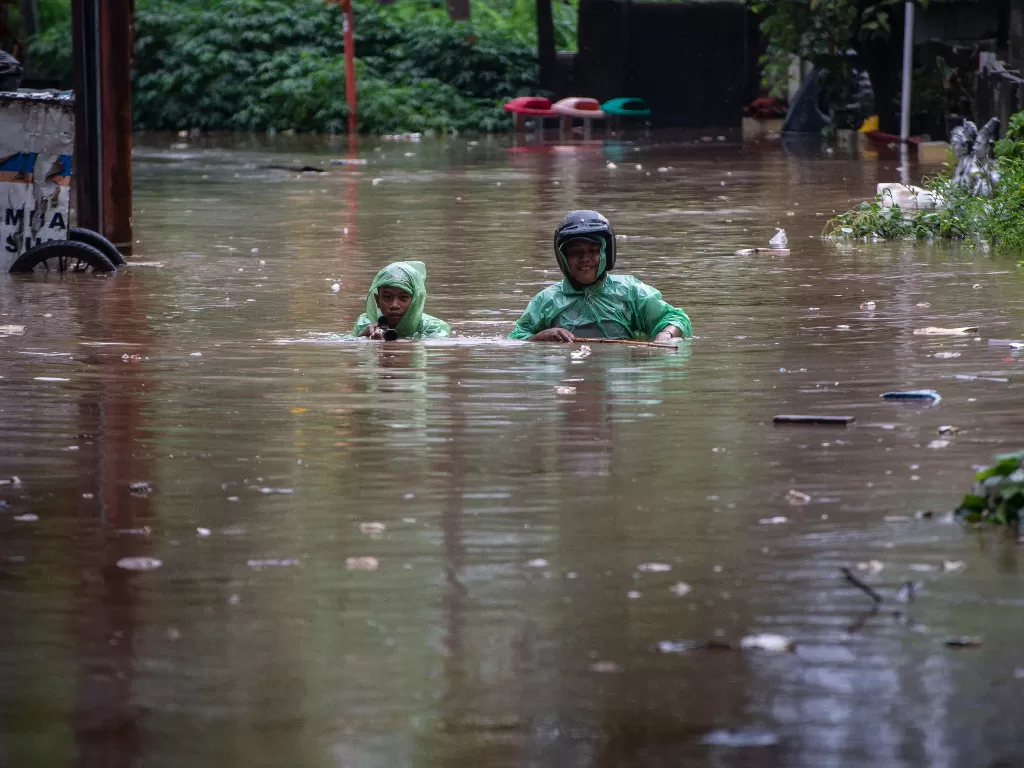 Warga berjalan melintasi genangan banjir di kawasan Karet Semanggi, Jakarta, Rabu (1/1/2020). Banjir tersebut disebabkan karena tingginya intensitas hujan yang mengguyur sejak Selasa (31/12/2019). (ANTARA FOTO/Aprillio Akbar/foc).