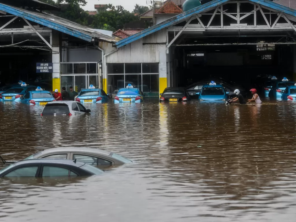 Warga mengevakuasi mobil taksi di pool taksi Kramat Jati, Jalan Raya Pondok Gede, Jakarta, Rabu (1/1/2020). Banjir tersebut disebabkan karena tingginya intensitas hujan yang mengguyur sejak Selasa (31/12/2019). (ANTARA FOTO/Galih Pradipta/foc).