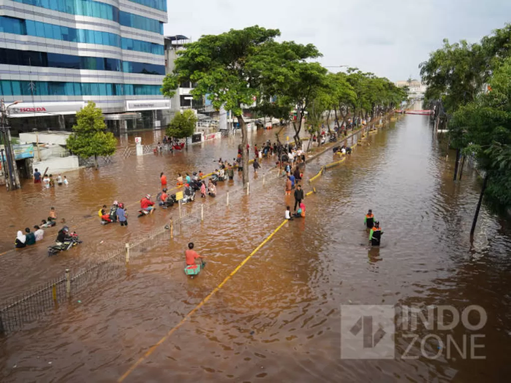 Warga melintasi jalanan yang tergenang banjir di Jalan Daan Mogot, Jakarta, Kamis (2/1/2020). INDOZONE/Arya Manggala