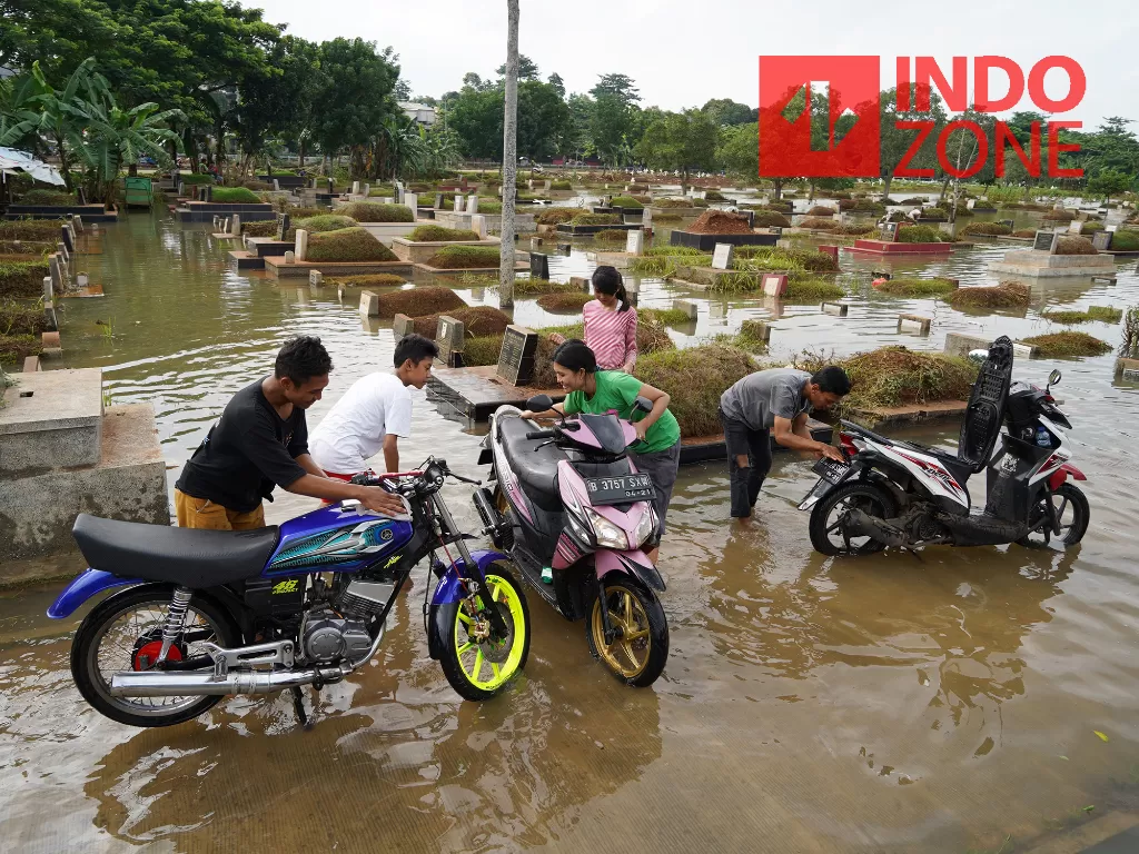  Warga mencuci motor di area makam yang tergenang banjir di Tempat Pemakaman Umum Tanah Kusir, Jakarta, Jumat (3/1/2020). INDOZONE/Arya Manggala