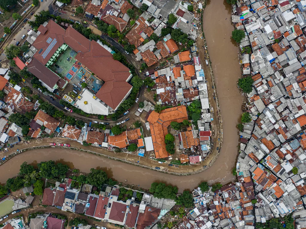 Foto udara suasana wilayah bantaran sungai Ciliwung yang belum dinormalisasi (bawah) dan yang sudah dinormalisasi (kiri) di kawasan Bukit Duri, Jakarta. (Antara/Muhammad Adimaja)