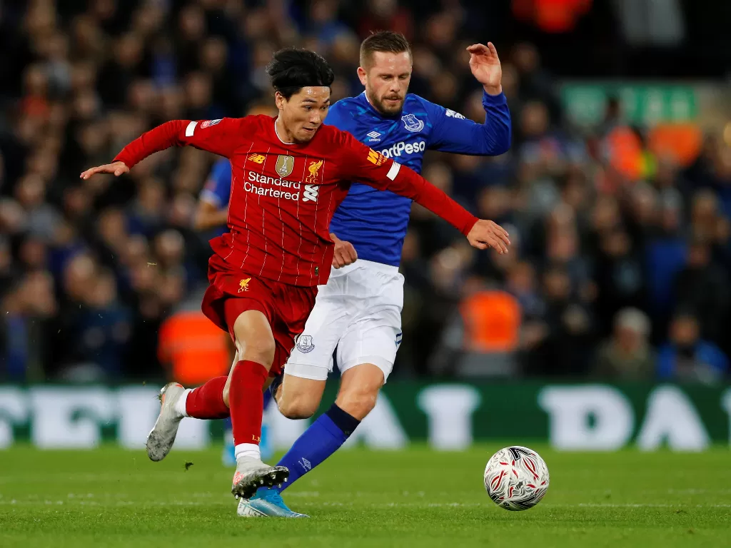 Pemain Liverpool Takumi Minamino berebut bola dengan pemain Everton Gylfi Sigurdsson pada pertandingan babak ketiga Piala FA di Stadion Anfield, Minggu (5/1). REUTERS/Phil Noble