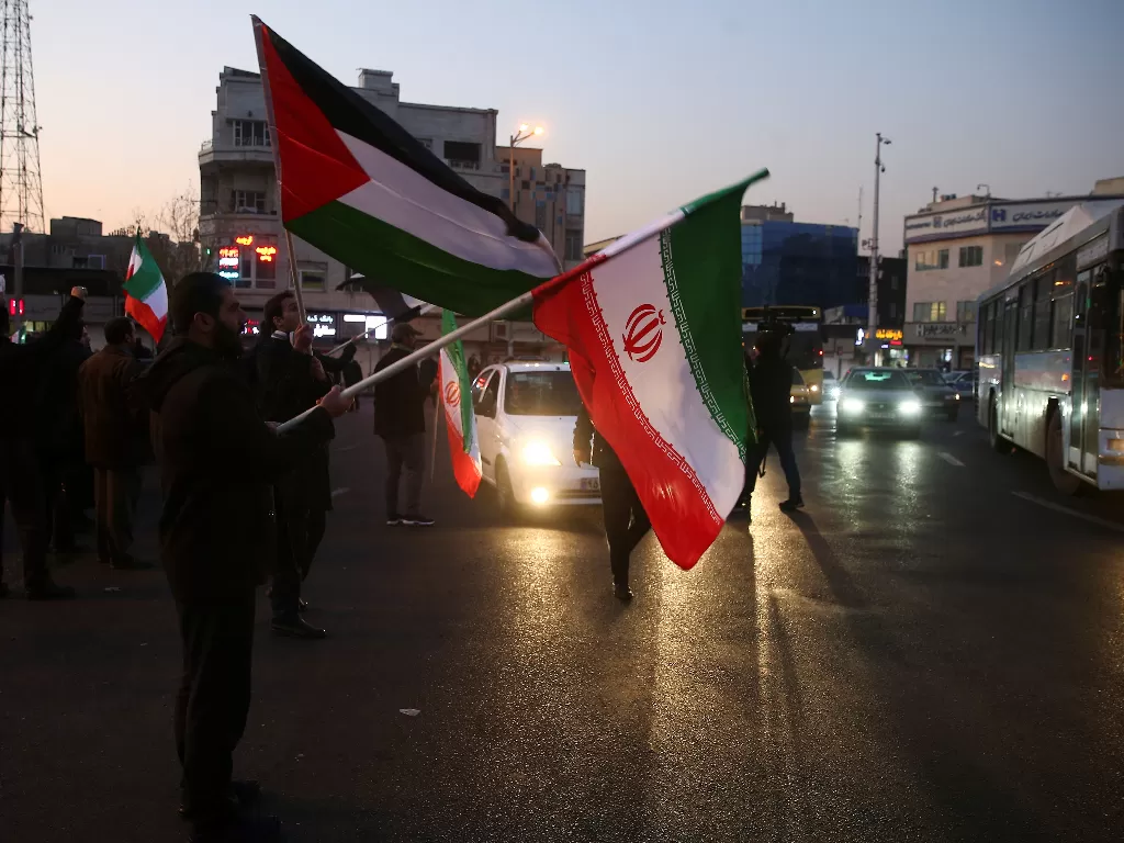 Warga merayakan serangan misil Iran ke pangkalan militer koalisi pimpinan Amerika Serikat di Irak, Rabu (8/1/2020) dinihari waktu setempat. (WANA/Nazanin Tabatabaee via REUTERS)