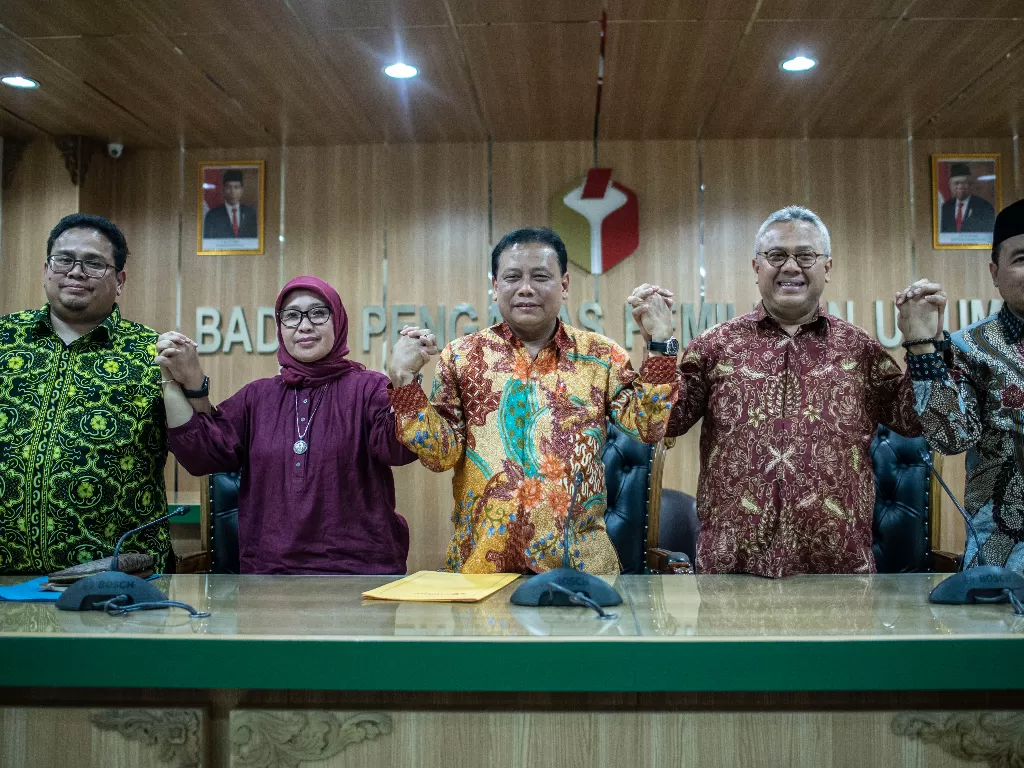 Ketua Bawaslu Abhan (tengah), hingga Ketua KPU Arief Budiman (kedua kanan), bergandeng tangan bersama usai memberikan keterangan pers hasil Rapat Tripartit, Jumat (10/1/2020). (ANTARA FOTO/Aprillio Akbar)