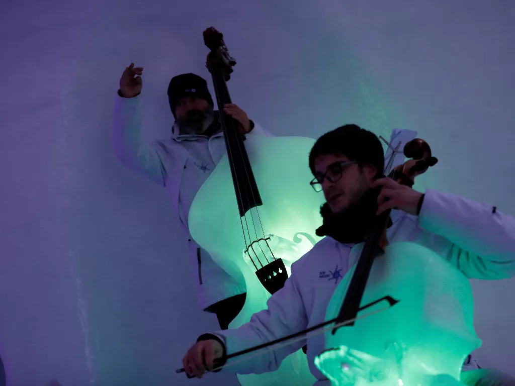 Dua orang musisi beraksi memainkan alat musik yang terbuat dari es dalam perhelatan Ice Music Festival di Italia, Kamis (9/1). (REUTERS/Yara Nardi)