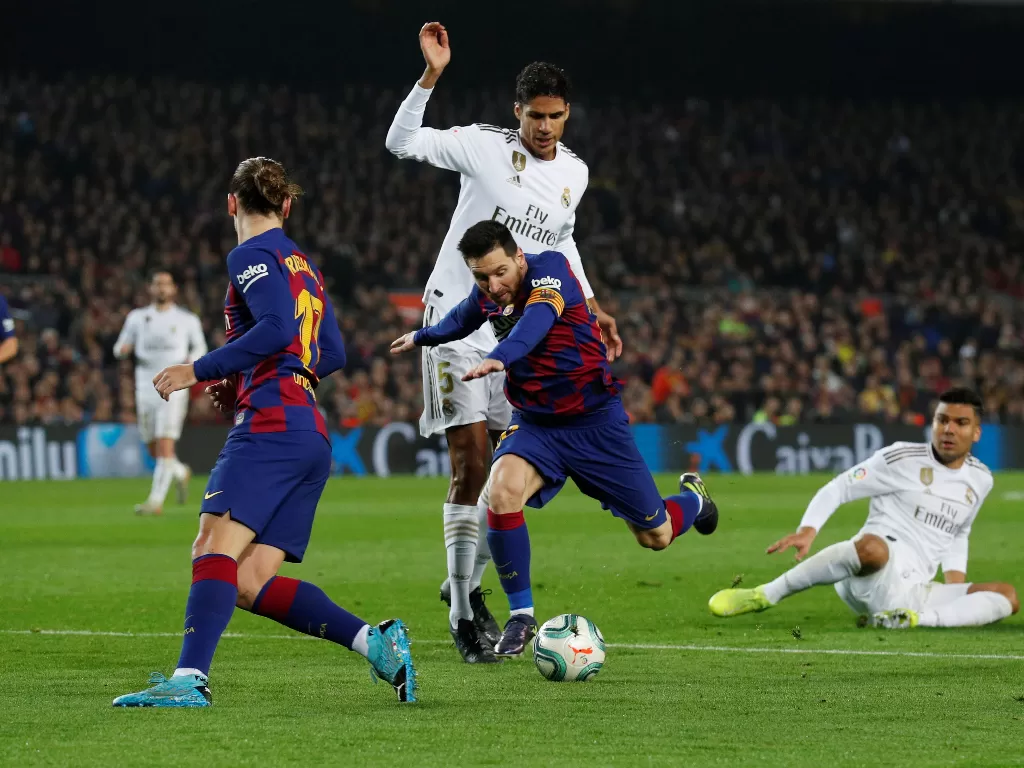 Raphael Varane sedang merebut bola dari Lionel Messi. (REUTERS/Albert Gea)