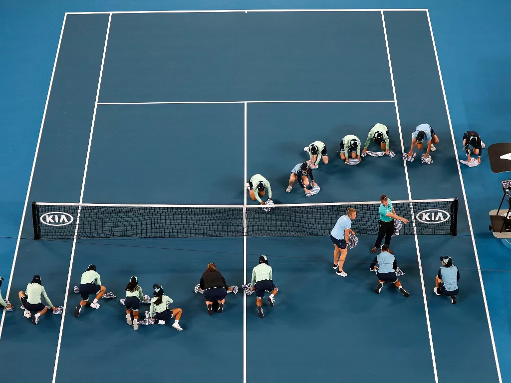  Petugas mengeringkan lapangan dengan handuk saat pertandingan putaran pertama Australia Open 2020 antara Roger Federer dan Steve Johnson di Rod Laver Arena, Australia, Senin (20/1/2020). (REUTERS/Issei Kato)